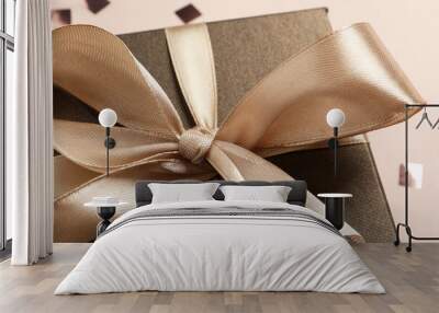 Beautiful gift box with bow on beige background, closeup view Wall mural