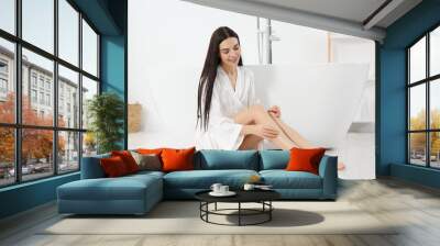 Beautiful happy woman wearing stylish bathrobe on floor near tub in bathroom Wall mural