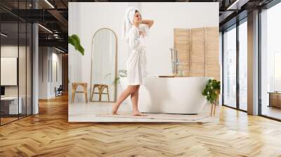 Beautiful happy woman wearing white robe near tub in bathroom Wall mural