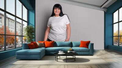 Beautiful overweight mature woman with charming smile on light grey background. Space for text Wall mural