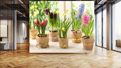 Beautiful spring flowers in wrapped pots on white wooden window sill Wall mural