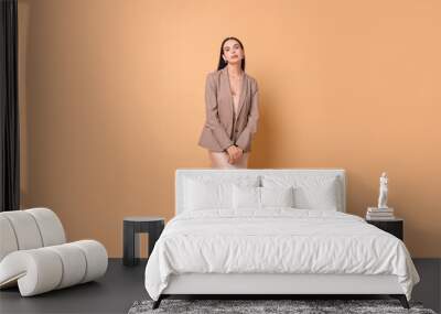 Beautiful woman in stylish jacket and beige dress on pale orange background Wall mural