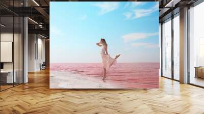 Beautiful woman posing near pink lake on sunny day Wall mural