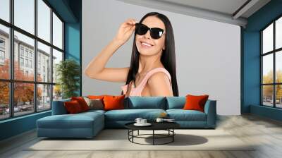 Beautiful woman wearing sunglasses on grey background Wall mural