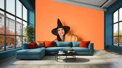 Beautiful woman wearing witch costume with pumpkin for Halloween party on yellow background, space for text Wall mural