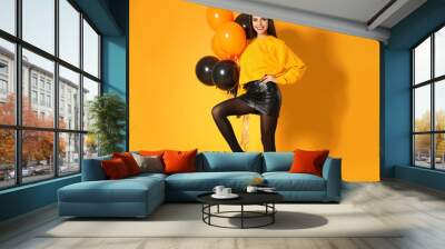 beautiful woman with balloons and pumpkins on yellow background. halloween party Wall mural