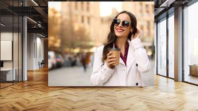 Beautiful woman with cup of coffee on city street. Autumn walk Wall mural