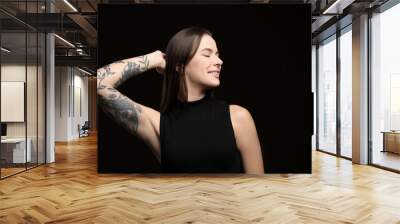 Beautiful woman with tattoos on arm against black background Wall mural