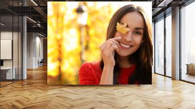 Beautiful woman with yellow leaf in sunny park. Autumn walk Wall mural