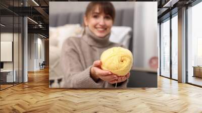 Beautiful woman with yellow yarn at home, selective focus. Knitting material Wall mural