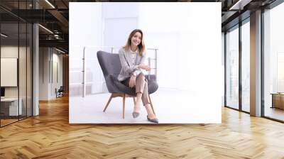 Beautiful young businesswoman sitting in armchair indoors. Space for text Wall mural