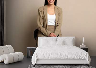 Beautiful young businesswoman sitting on stool near beige wall Wall mural