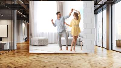 Beautiful young couple dancing in living at home Wall mural