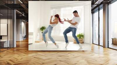 Beautiful young couple dancing in living room Wall mural