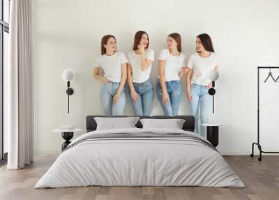 Beautiful young ladies in jeans and white t-shirts near light wall indoors. Woman's Day Wall mural