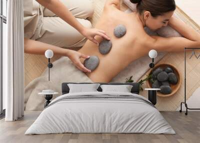 Beautiful young woman getting hot stone massage in spa salon, top view Wall mural