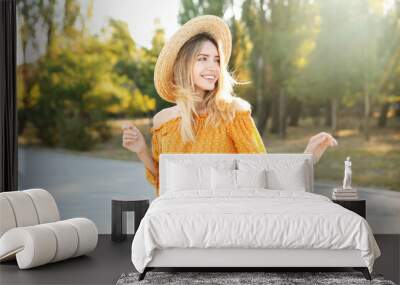 Beautiful young woman in stylish yellow dress and straw hat outdoors Wall mural