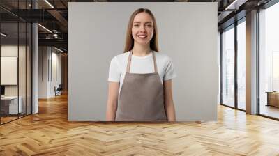 Beautiful young woman wearing kitchen apron on grey background. Mockup for design Wall mural