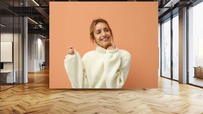 Beautiful young woman wearing knitted sweater on light brown background Wall mural