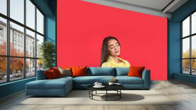 Beautiful young woman wearing yellow warm sweater on red background Wall mural