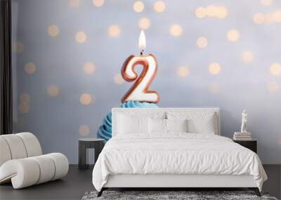 Birthday cupcake with number two candle on table against festive lights Wall mural