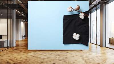 Black man's underwear and cotton flowers on light blue background, flat lay. Space for text Wall mural