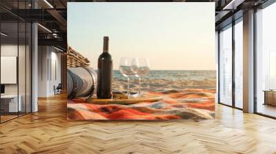 Blanket with picnic basket, bottle of wine and glasses on sandy beach near sea, space for text. Banner design Wall mural