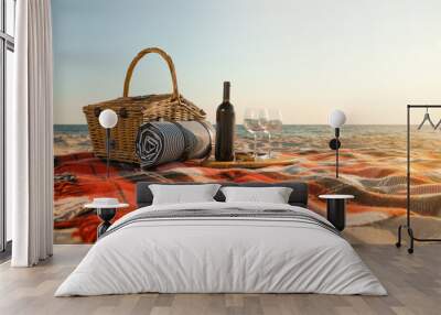 Blanket with picnic basket, bottle of wine and glasses on sandy beach near sea, space for text Wall mural