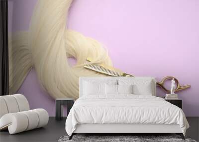 Blonde hair strand and professional scissors on violet background, top view Wall mural