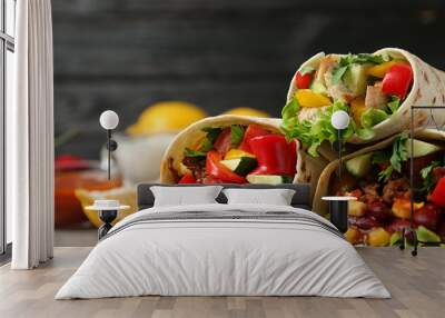 Board with delicious meat tortilla wraps on light table against black background, closeup Wall mural