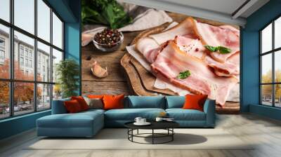 Board with slices of raw bacon on wooden table, closeup Wall mural