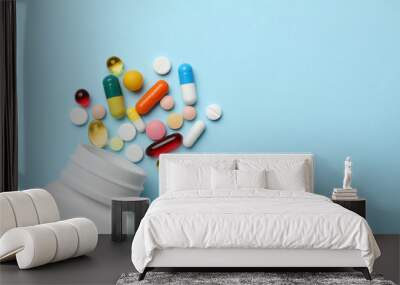 Bottle and scattered pills on color background, top view. Space for text Wall mural