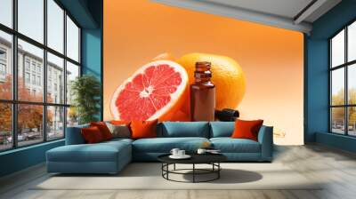 Bottle of essential oil and fresh grapefruits on color background Wall mural