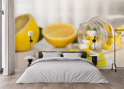 Bottle with vitamin pills and lemon on light table, closeup Wall mural