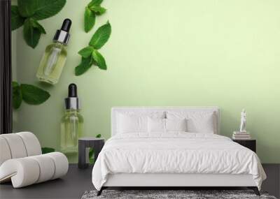 Bottles of essential oil and mint on light green background, flat lay. Space for text Wall mural