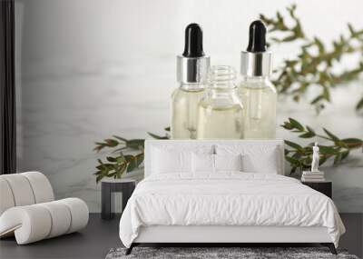 Bottles of eucalyptus essential oil and plant branches on white marble table. Space for text Wall mural