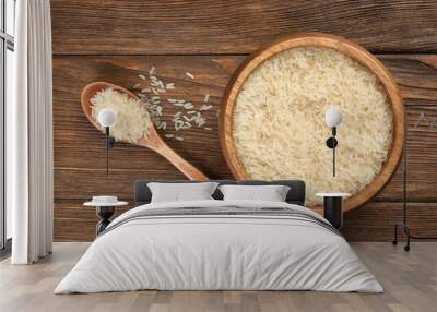 Bowl and spoon with white rice on wooden table, flat lay Wall mural