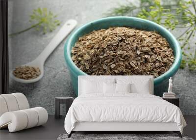 Bowl of dry seeds, spoon and fresh dill on grey table, closeup Wall mural