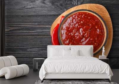 Bowl of hot chili sauce with red peppers on dark wooden background, top view. Space for text Wall mural