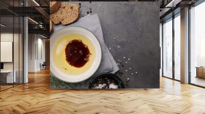 Bowl of organic balsamic vinegar with oil, spices and bread slices on grey table, flat lay. Space for text Wall mural