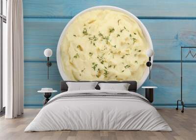 Bowl of tasty mashed potato with rosemary on light blue wooden table, top view Wall mural