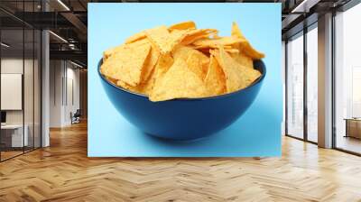 Bowl of tasty Mexican nachos chips on light blue background Wall mural