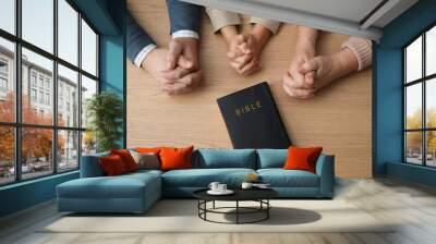 Boy and his godparents praying together at wooden table, top view Wall mural