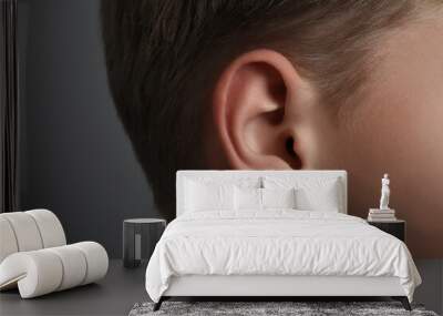 Boy on grey background, closeup of ear Wall mural