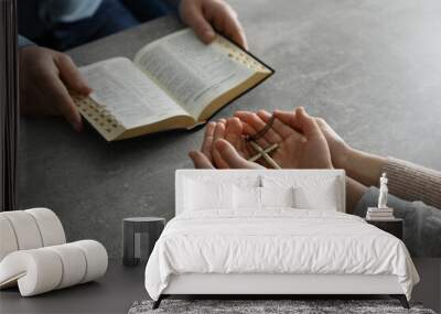 Boy praying and reading Bible with his godparents at grey table, closeup Wall mural