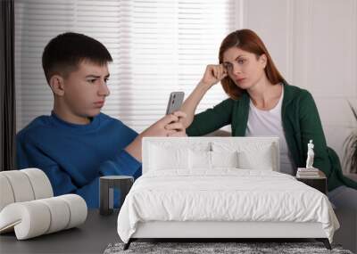 Boy using smartphone and ignoring his upset mother at home. Teenager problems Wall mural