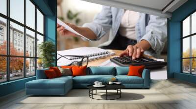 Budget planning. Woman using calculator while working with accounting document at table indoors, closeup Wall mural