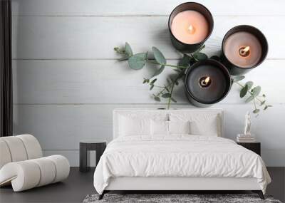 Burning candles and green branches on white wooden table, flat lay. Space for text Wall mural