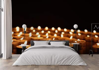 Burning candles on dark surface against black background Wall mural