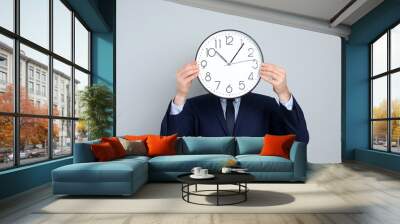 Businessman holding clock on grey background. Time management Wall mural